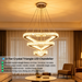 3-tier silver crystal triangle LED chandelier suspended above a modern dining table, emitting warm white light – Mega Lighting