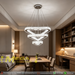 3-tier silver crystal triangle LED chandelier suspended above a modern dining table, emitting warm white light – Mega Lighting