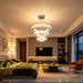 3-tier white circular LED ring chandelier suspended above a modern bed, emitting warm white light – Mega Lighting