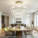 5-ring white LED pendant chandelier with cascading 30-60cm rings, warm glow above a modern dining table.