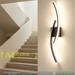 Modern 60cm black curved LED wall light installed on a staircase wall, emitting warm white light – Mega Lighting
