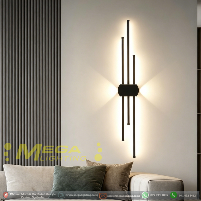 Modern staggered vertical LED wall sconce with three rods, mounted beside a sofa – Mega Lighting