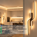 63cm matte black twisted dual-wavy LED wall light installed in a modern bedroom, emitting warm white light – Mega Lighting
