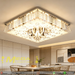 Modern LED crystal ceiling light with faceted crystal pendants and mirrored finish, installed in a contemporary living room, warm 3000K glow.