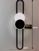 60cm matte black geometric circular-oval LED wall light installed in a modern hallway, emitting warm white light – Mega Lighting
